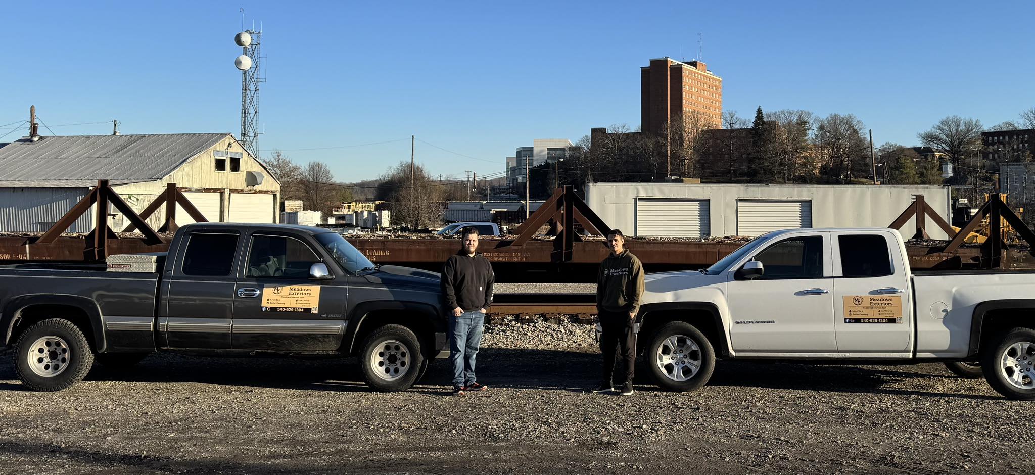 Meadows Exteriors company trucks with team members at job site showcasing professional fleet